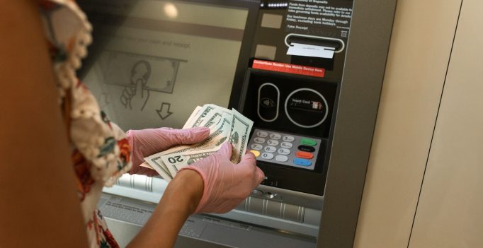 Person Counting Money in front of ATM